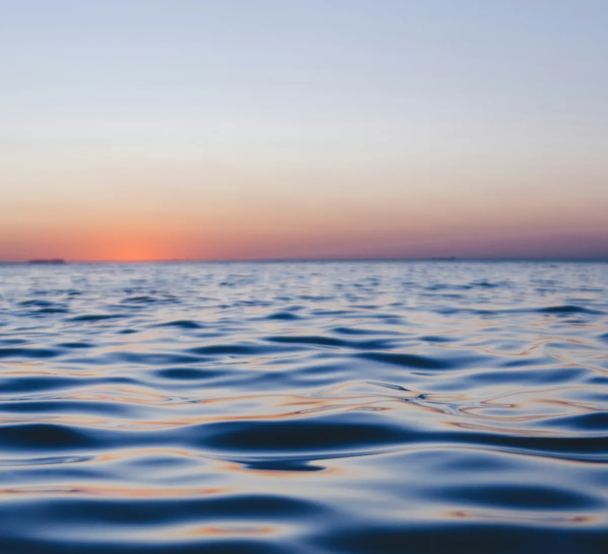 Calm sea at dusk, the last of the sunset settling low across gentle water.