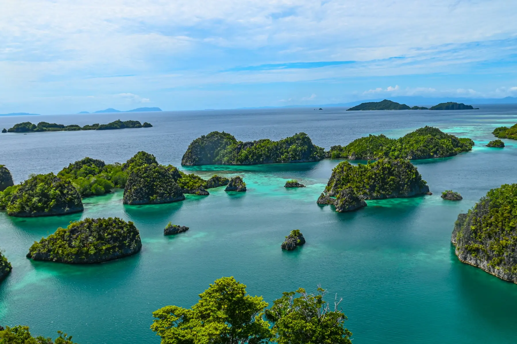 Limestone islands scattered across bright turquoise shallows under a wide, calm sky.